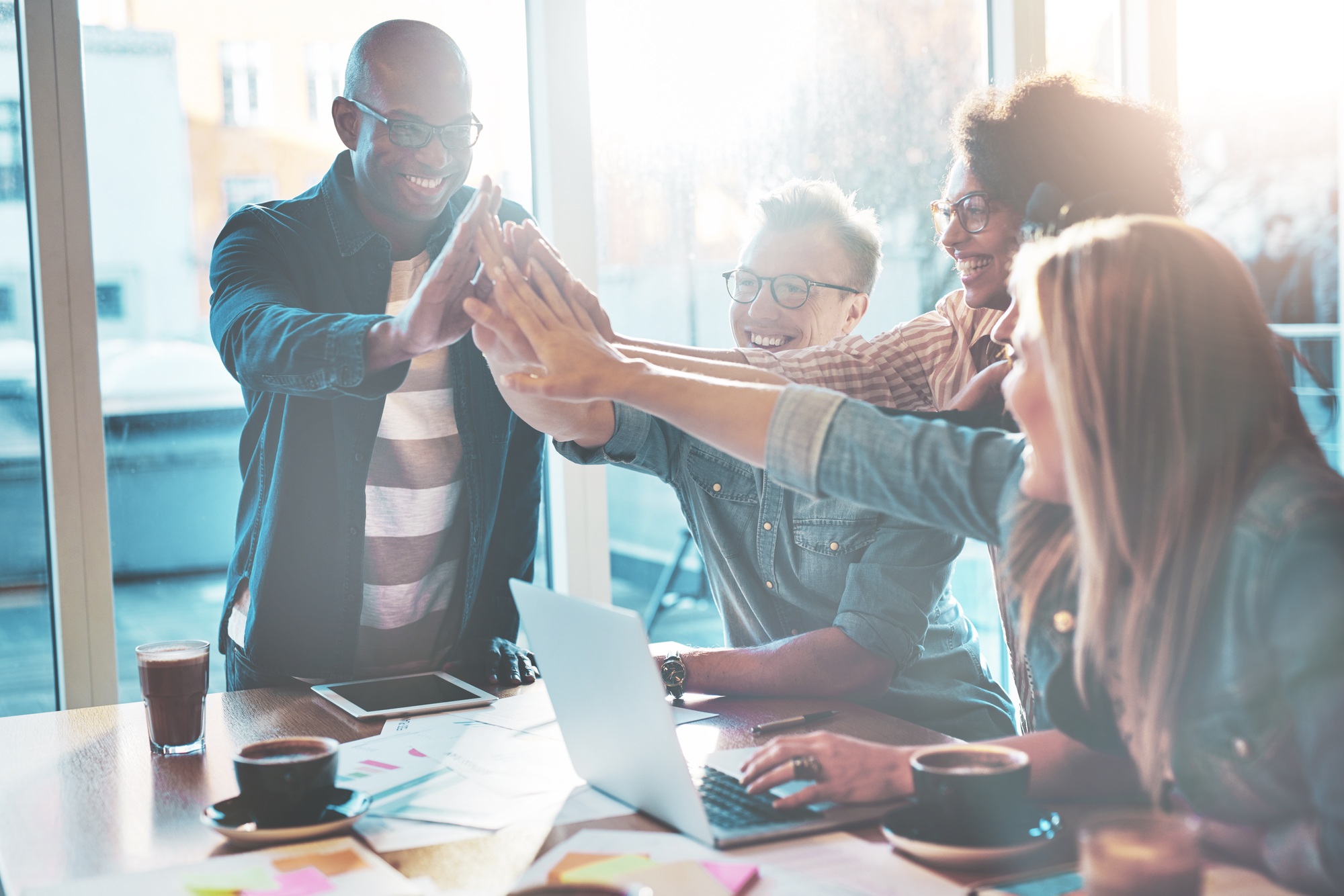 High fiving coworkers at table in office